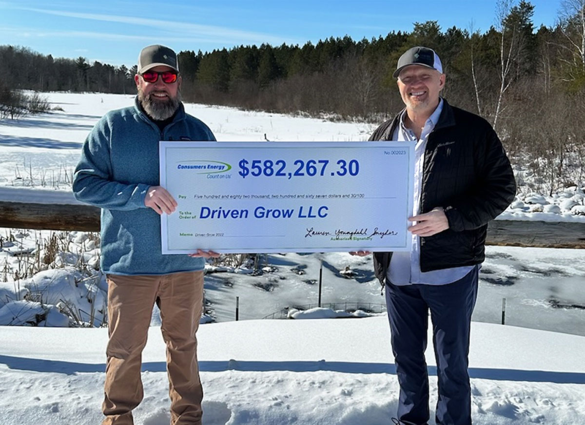 Two men holding an oversized check for over $582,000.